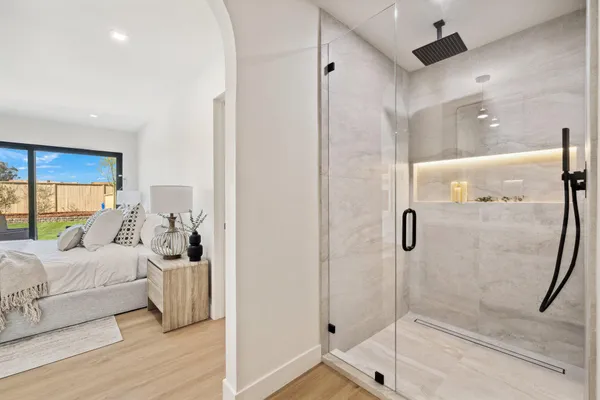 a bedroom with a bed and a glass door shower