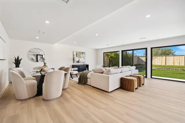 a living room with furniture large windows and wooden floor