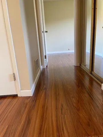 an empty room with wooden floor and entrance