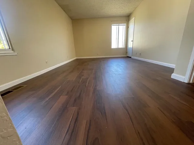 a view of an empty room with wooden floor and window