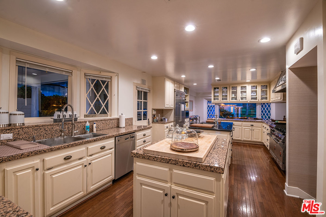 20 Toluca Estates Drive Toluca Lake, CA 91602 - Photo 23 of 46 a kitchen with a sink dishwasher a stove and white cabinets with wooden floor