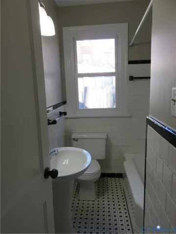 a bathroom with a sink a toilet a window and vanity