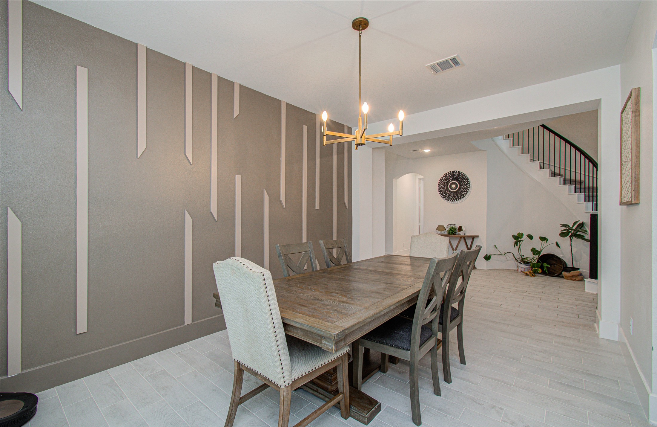 4211 Limestone Terrace Manvel, TX 77578 - Photo 6 of 33 This dining room features a modern design with a stylish accent wall and a contemporary chandelier. The space is open and airy, extending into a hallway with a staircase, enhancing the home's flow.