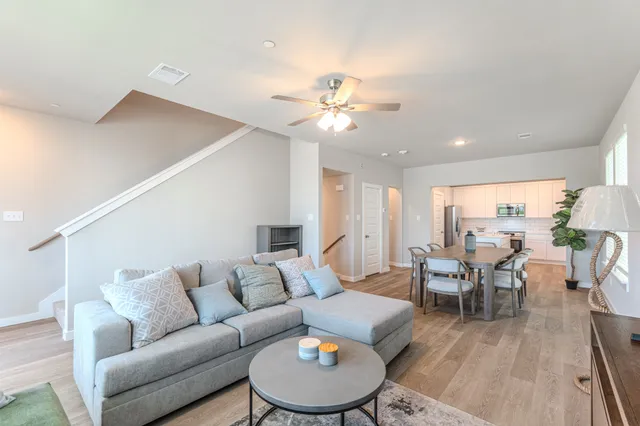 a living room with furniture kitchen view and a chandelier