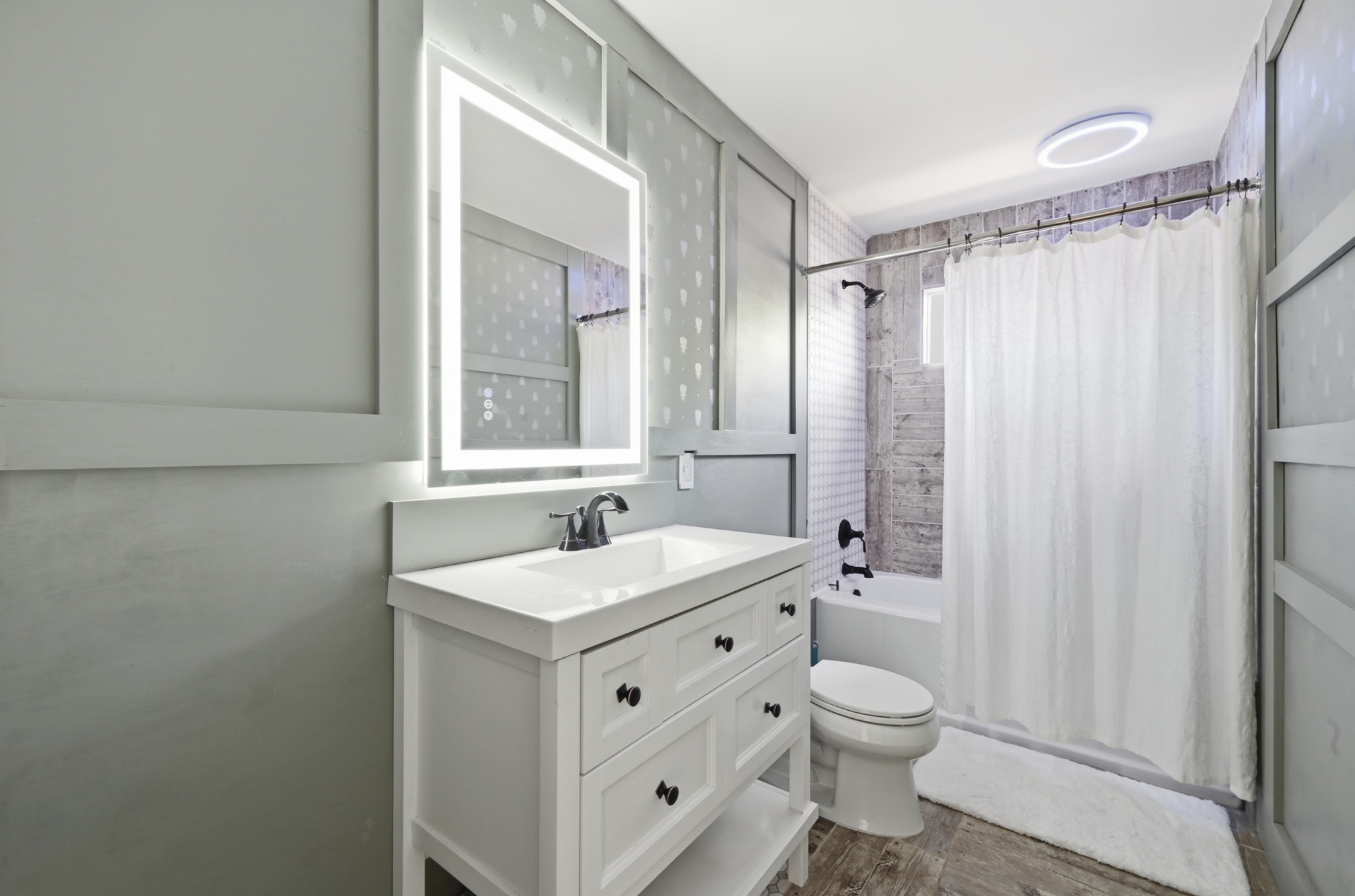 708 Shade Tree Drive Austin, TX 78748 - Photo 23 of 32 The full secondary bathroom is also tastefully modernized with a contemporary vanity, backlit designer mirror, wall accents, and a shower/tub combo with stylish tiled backsplash and a unique modern light fixture above.