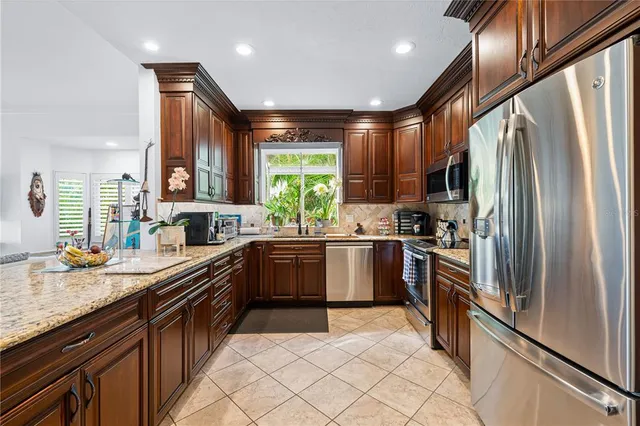 a kitchen with stainless steel appliances granite countertop a refrigerator a sink dishwasher a stove and a refrigerator