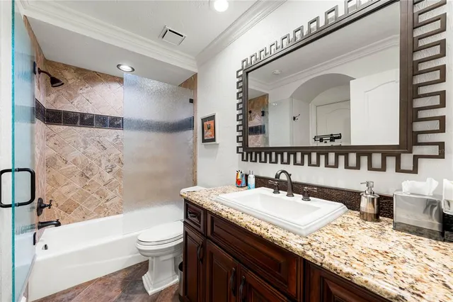 a bathroom with a granite countertop sink a toilet a mirror and bathtub