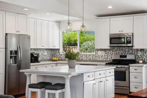 a kitchen with stainless steel appliances kitchen island granite countertop a sink a stove a refrigerator and cabinets