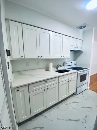 a kitchen with granite countertop white cabinets and stainless steel appliances