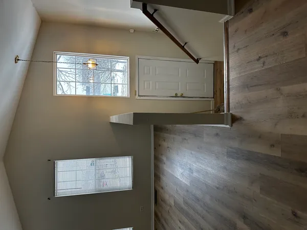 a view of an empty room with wooden floor and a window