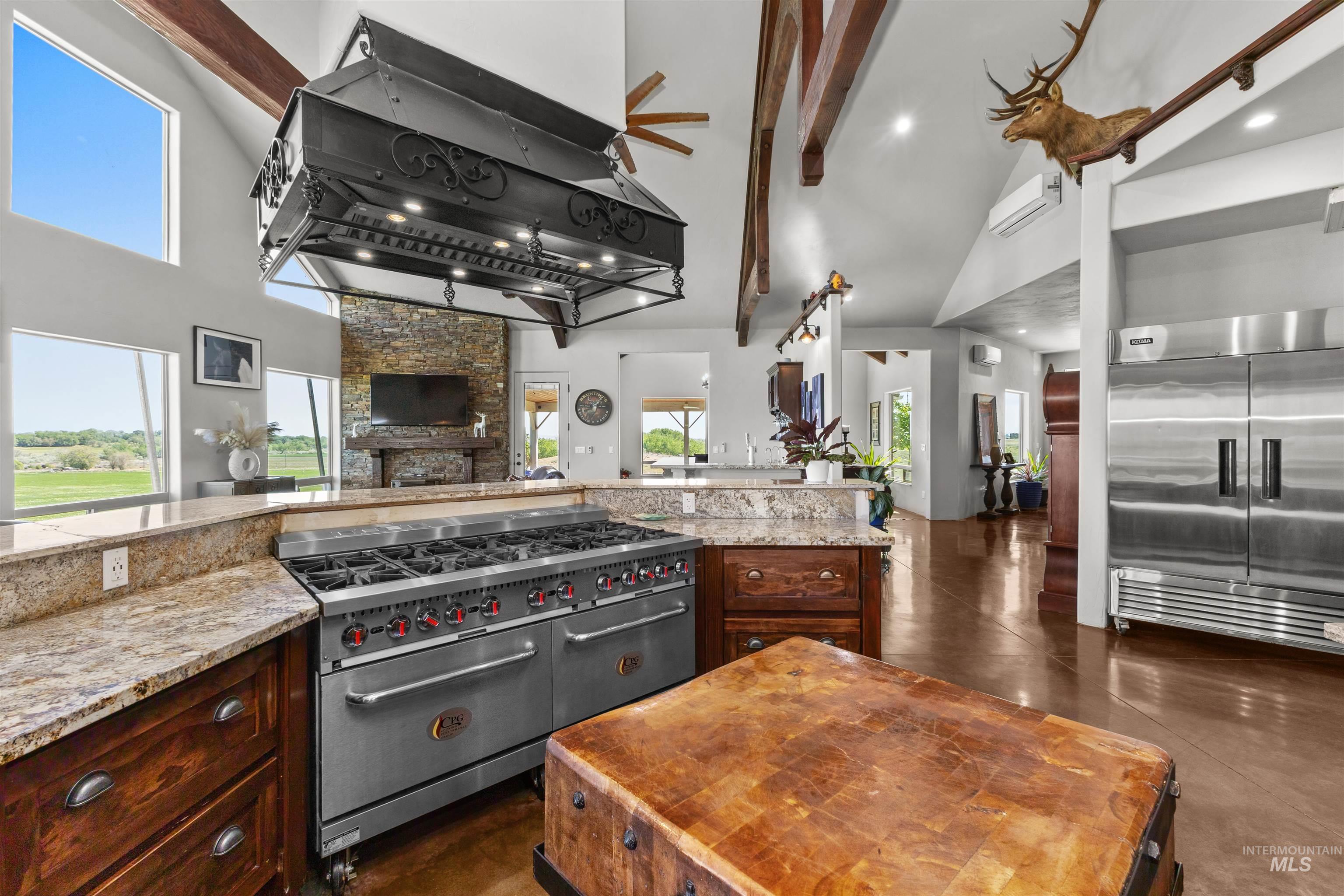 1030 Desert Glen Road Adrian, OR 97901 - Photo 28 of 47 Gourmet kitchen featuring a large professional-grade range with an ornate custom range hood, ample stone countertops, and rich wood cabinetry