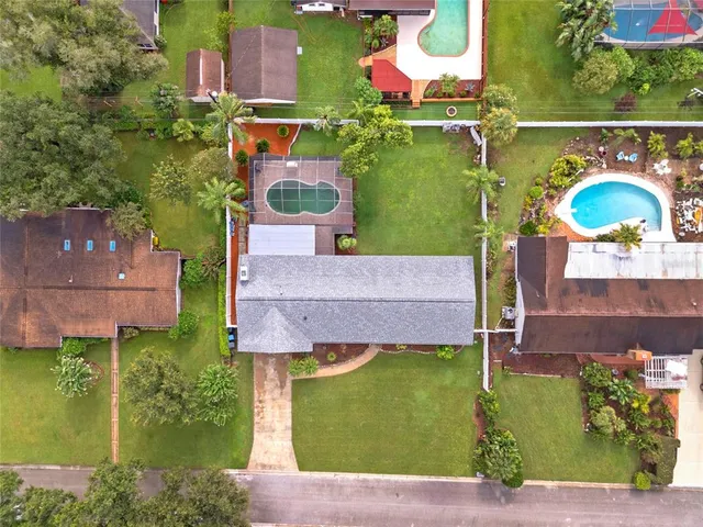 an aerial view of residential houses with outdoor space and trees
