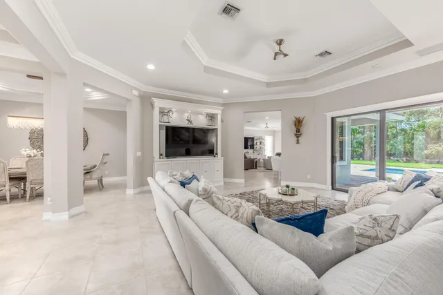 a living room with furniture a flat screen tv and large windows