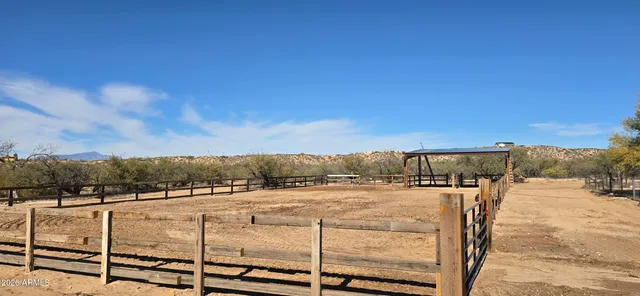 a view of a dining room and livingroom with furniture wooden floor a rug a painting and a chandelier