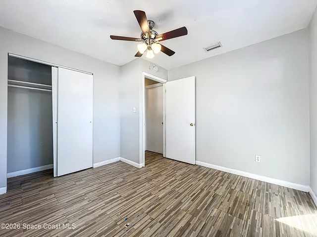 an empty room with wooden floor and a ceiling fan