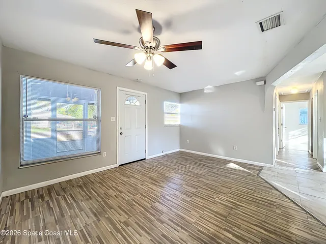 a view of an empty room with wooden floor and a window