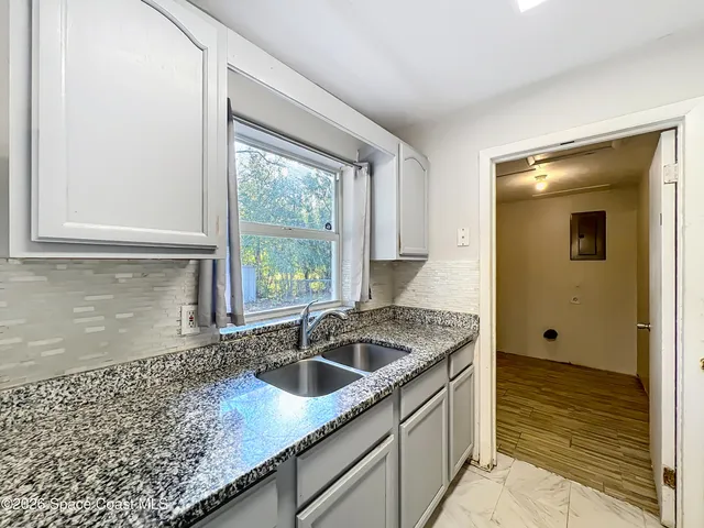 a kitchen with granite countertop a sink a counter top space and stainless steel appliances