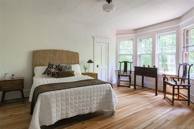 a bedroom with a bed and a potted plant on the dresser
