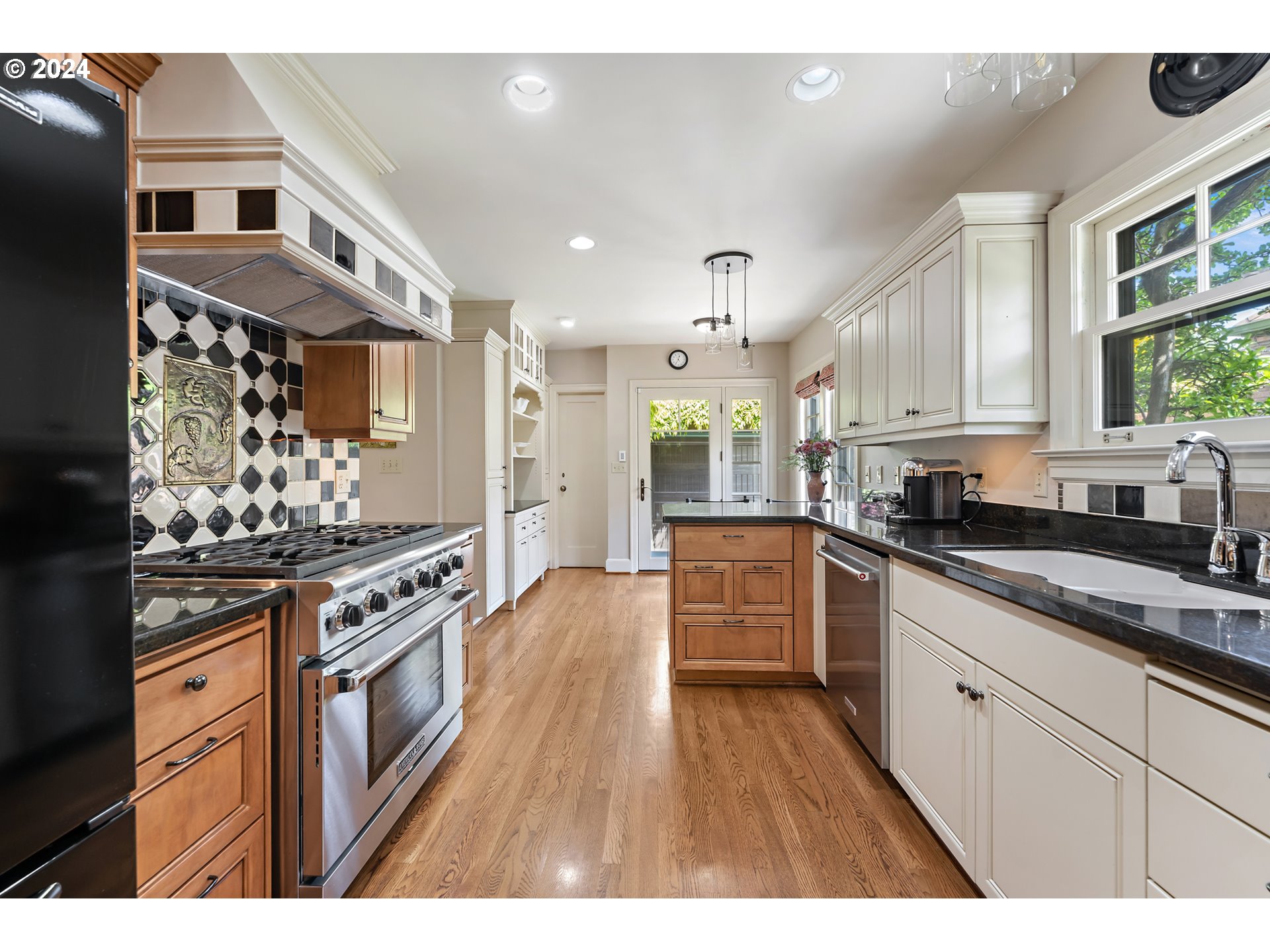 3433 Southeast Henry Street Portland, OR 97202 - Photo 12 of 48 a kitchen with stainless steel appliances granite countertop a stove a sink dishwasher and white cabinets with wooden floor