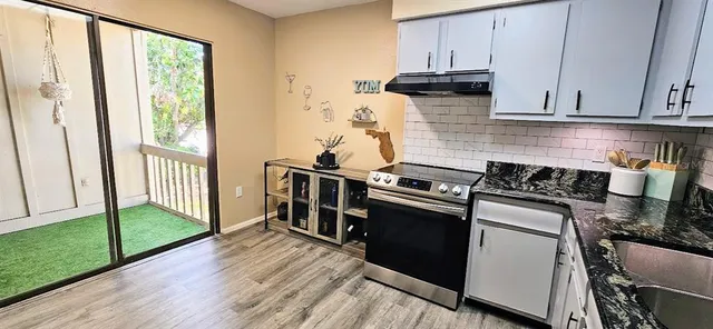a kitchen with stainless steel appliances granite countertop a stove a sink and white cabinets