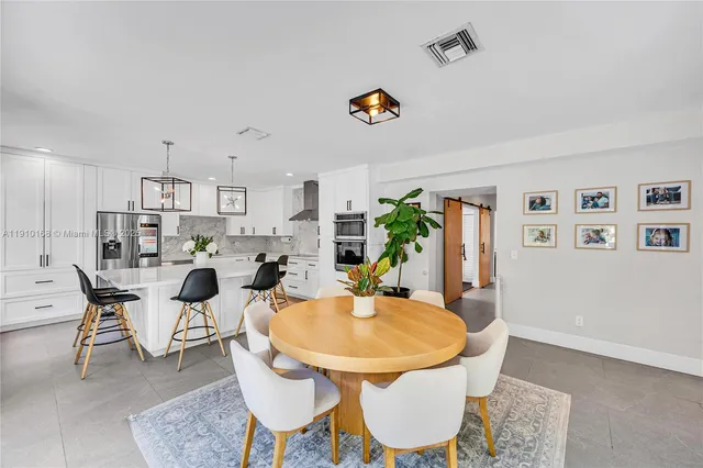 a kitchen with stainless steel appliances a table and chairs in it