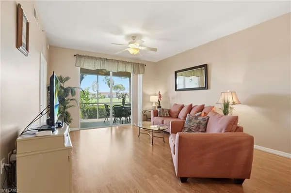 a living room with furniture large window and wooden floor