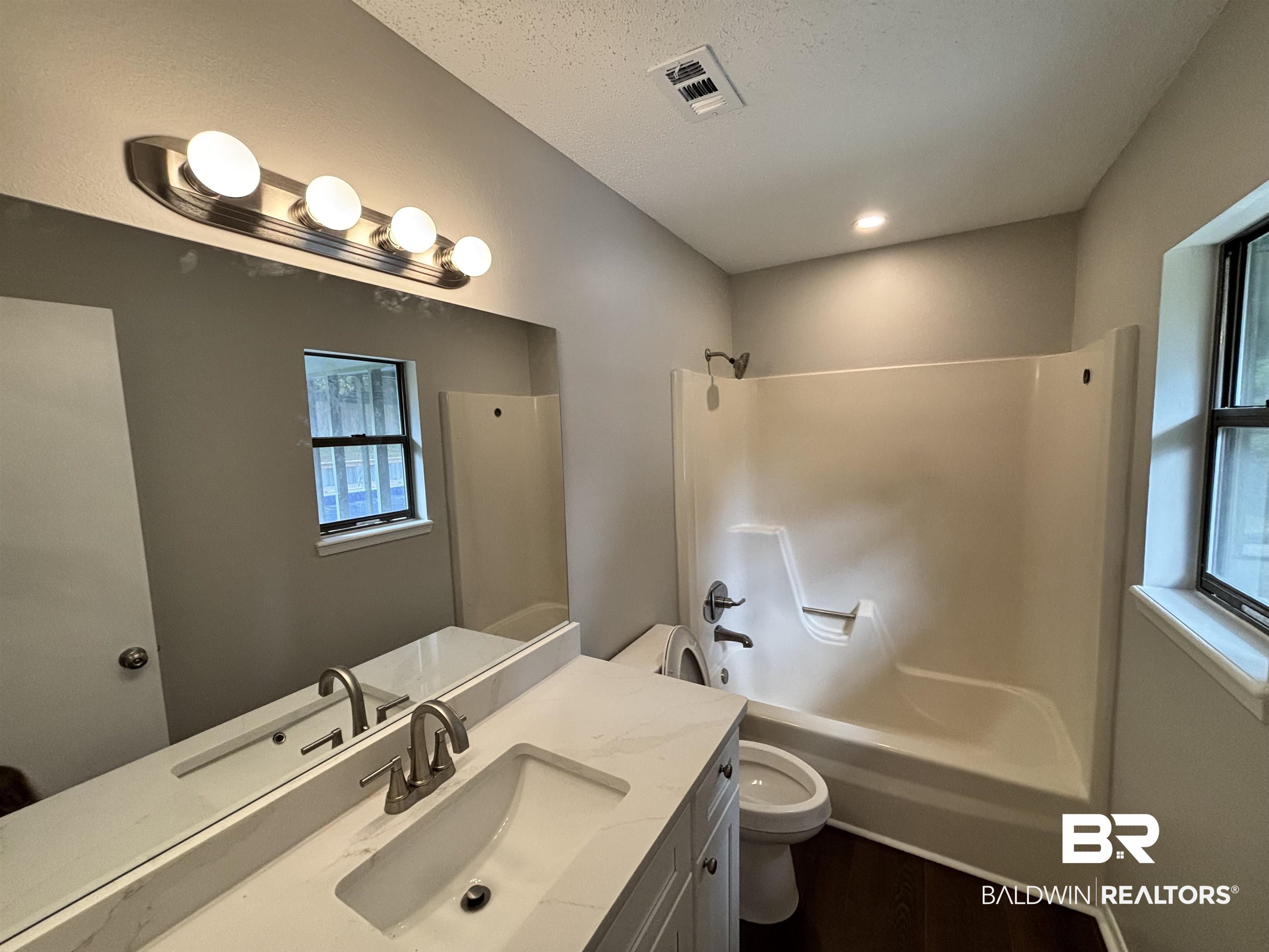 10 Soldiers Route Daphne, AL 36527 - Photo 19 of 26 Bathroom featuring vanity, bathing tub / shower combination, dark wood-style flooring, and a textured ceiling