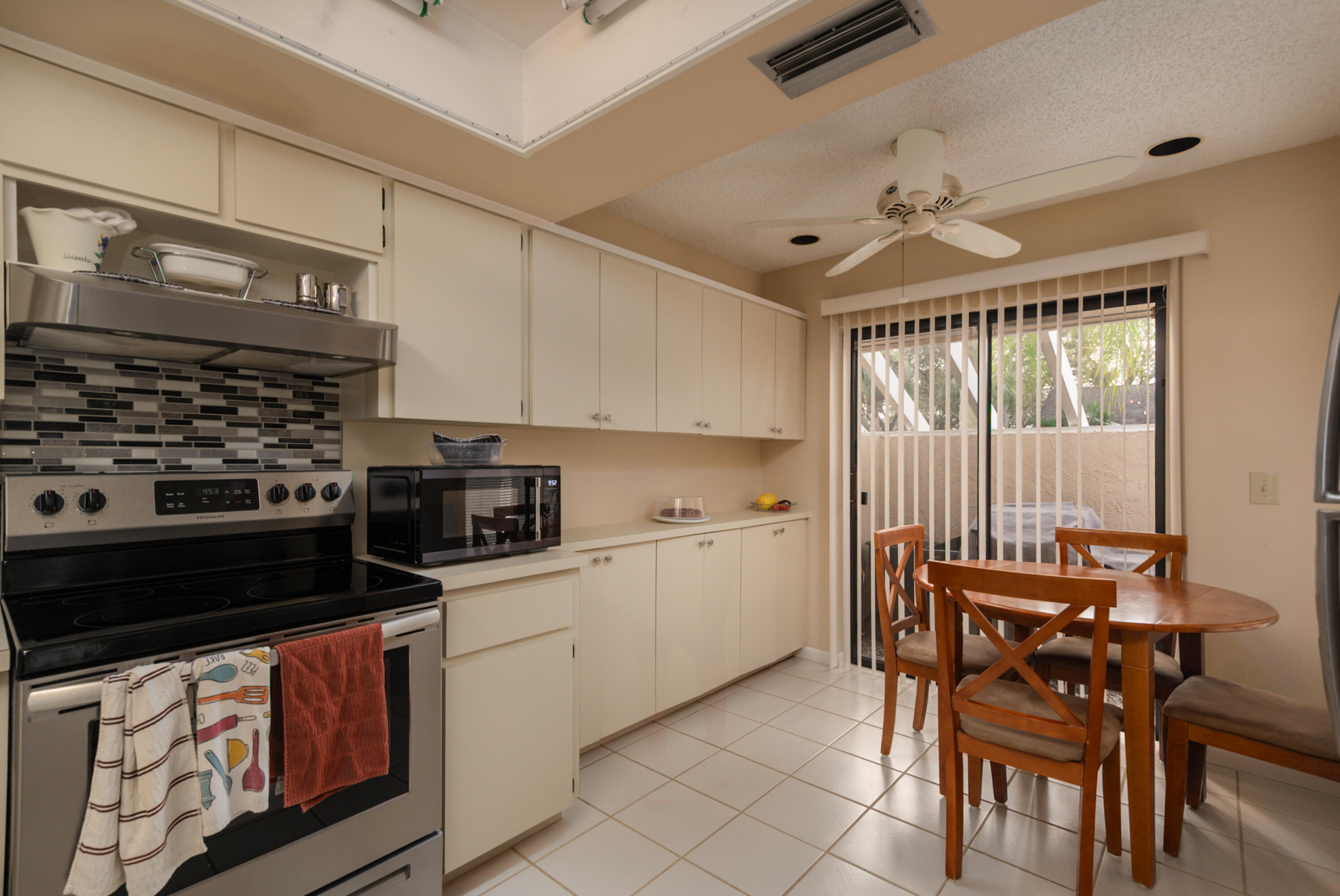 10867 Waterberry Court Boca Raton, FL 33498 - Photo 5 of 30 a kitchen with stainless steel appliances a stove a sink and chairs