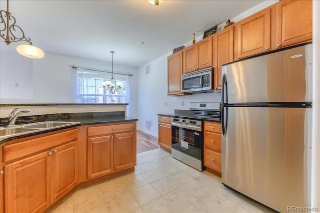 a kitchen with stainless steel appliances granite countertop a refrigerator a stove a sink and a cabinets