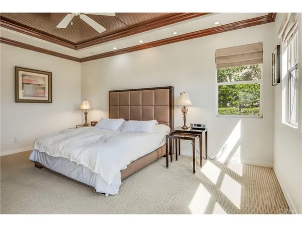 a bedroom with a bed painting on wall and a large window