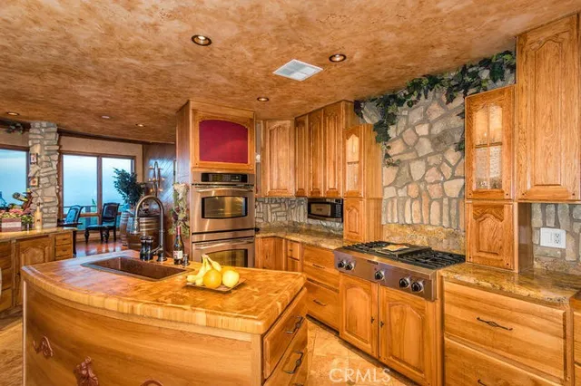 a kitchen with stainless steel appliances granite countertop a sink a stove and a wooden cabinets