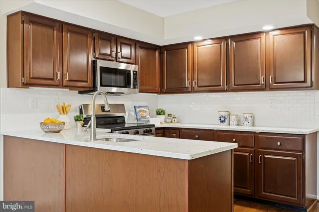 a kitchen with stainless steel appliances granite countertop a sink stove microwave and refrigerator