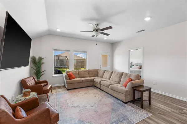 a living room with furniture ceiling fan and a flat screen tv