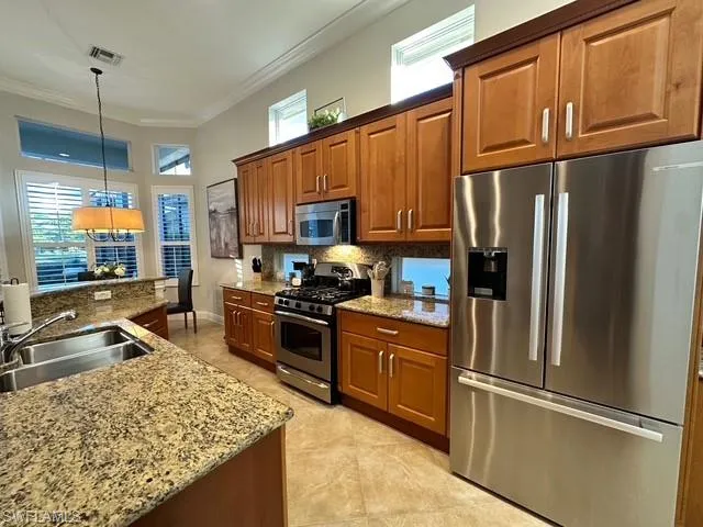 a kitchen with granite countertop a refrigerator stove and sink
