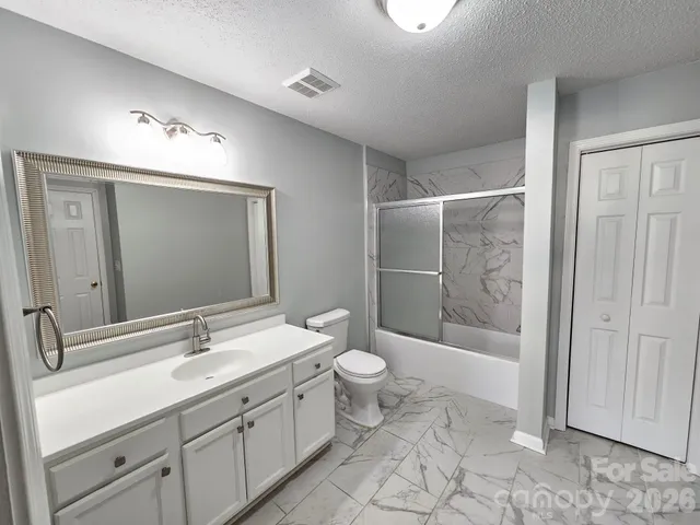 a bathroom with a double vanity sink toilet mirror and shower