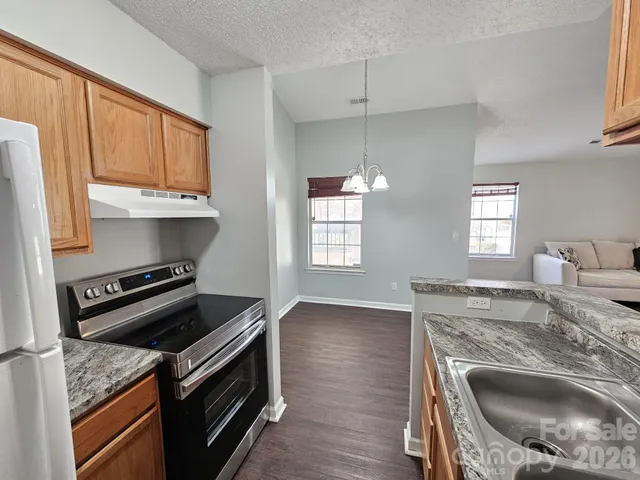 a kitchen with granite countertop a stove sink and microwave