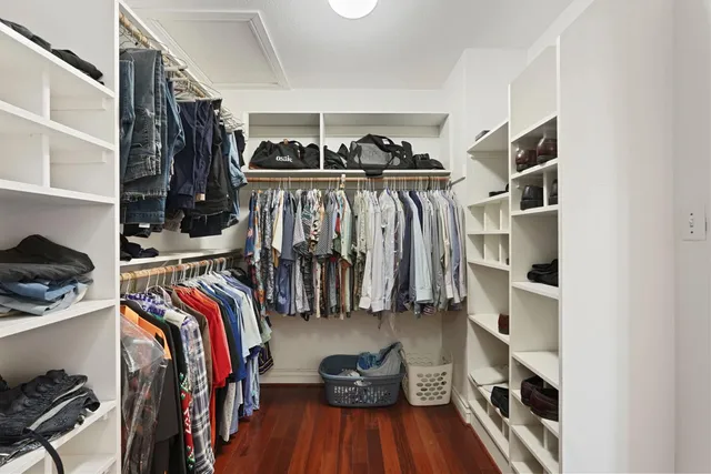 a bedroom with a bed and dresser with wooden floor