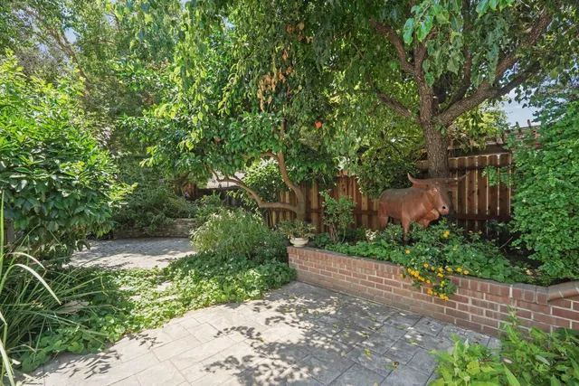a view of backyard of house with seating space and trees