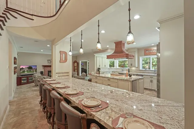a kitchen with kitchen island a stove a sink a dining table and chairs with wooden floor
