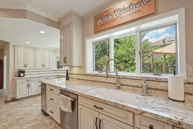 a kitchen with granite countertop white cabinets and a large window