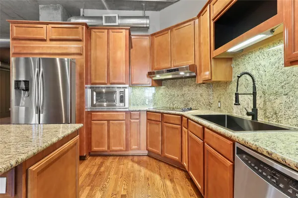 a kitchen with stainless steel appliances granite countertop a sink a counter space and a window