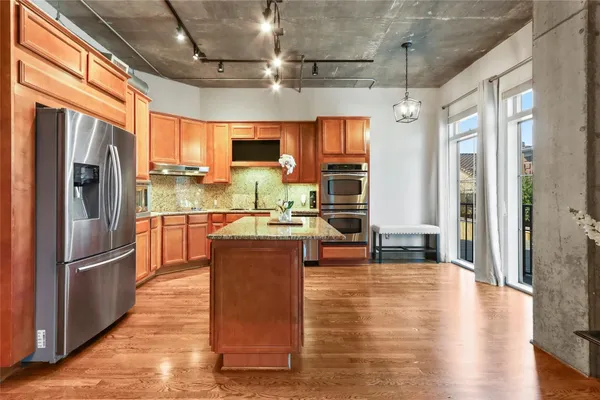 a kitchen with stainless steel appliances kitchen island granite countertop a stove and a view of living room