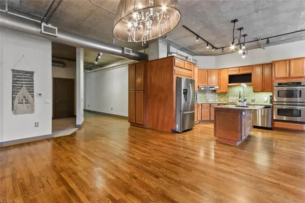 a kitchen with stainless steel appliances granite countertop a refrigerator a sink a stove and a refrigerator