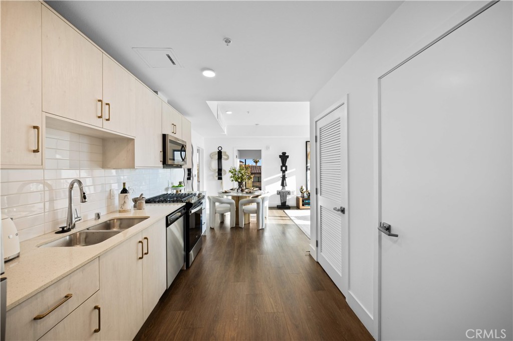 218 North El Molino Avenue, Unit 502 Pasadena, CA 91101 - Photo 6 of 35 a large white kitchen with lots of counter space a sink dishwasher and a stove with wooden floor