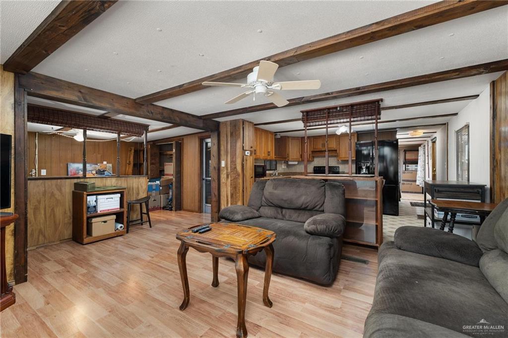 14610 Oak Street Harlingen, TX 78552 - Photo 4 of 16 Living area with beam ceiling, wood walls, light wood-style flooring, and a ceiling fan