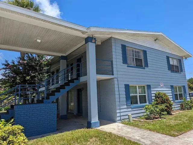 a view of a house with a yard and potted plants