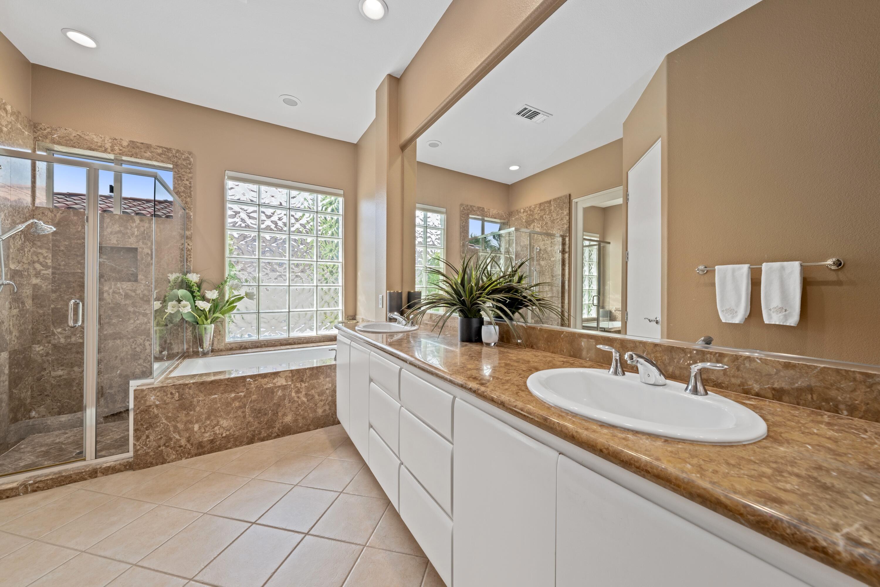 269 Loch Lomond Road Rancho Mirage, CA 92270 - Photo 32 of 53 a bathroom with a granite countertop sink a large mirror a bathtub and next to a window