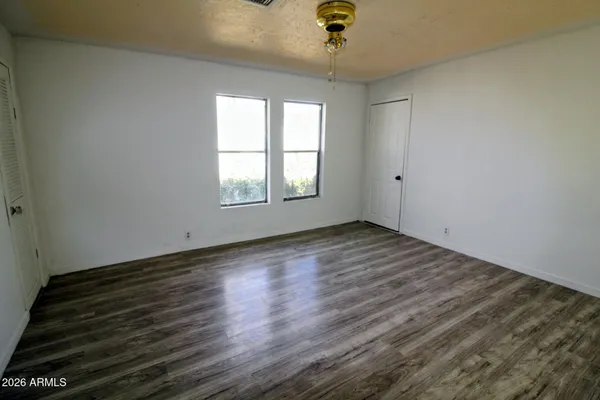 an empty room with wooden floor and windows