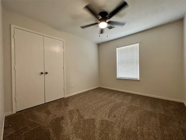 an empty room with a chandelier fan and windows
