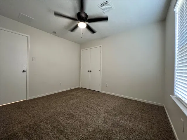 an empty room with a window and a fan